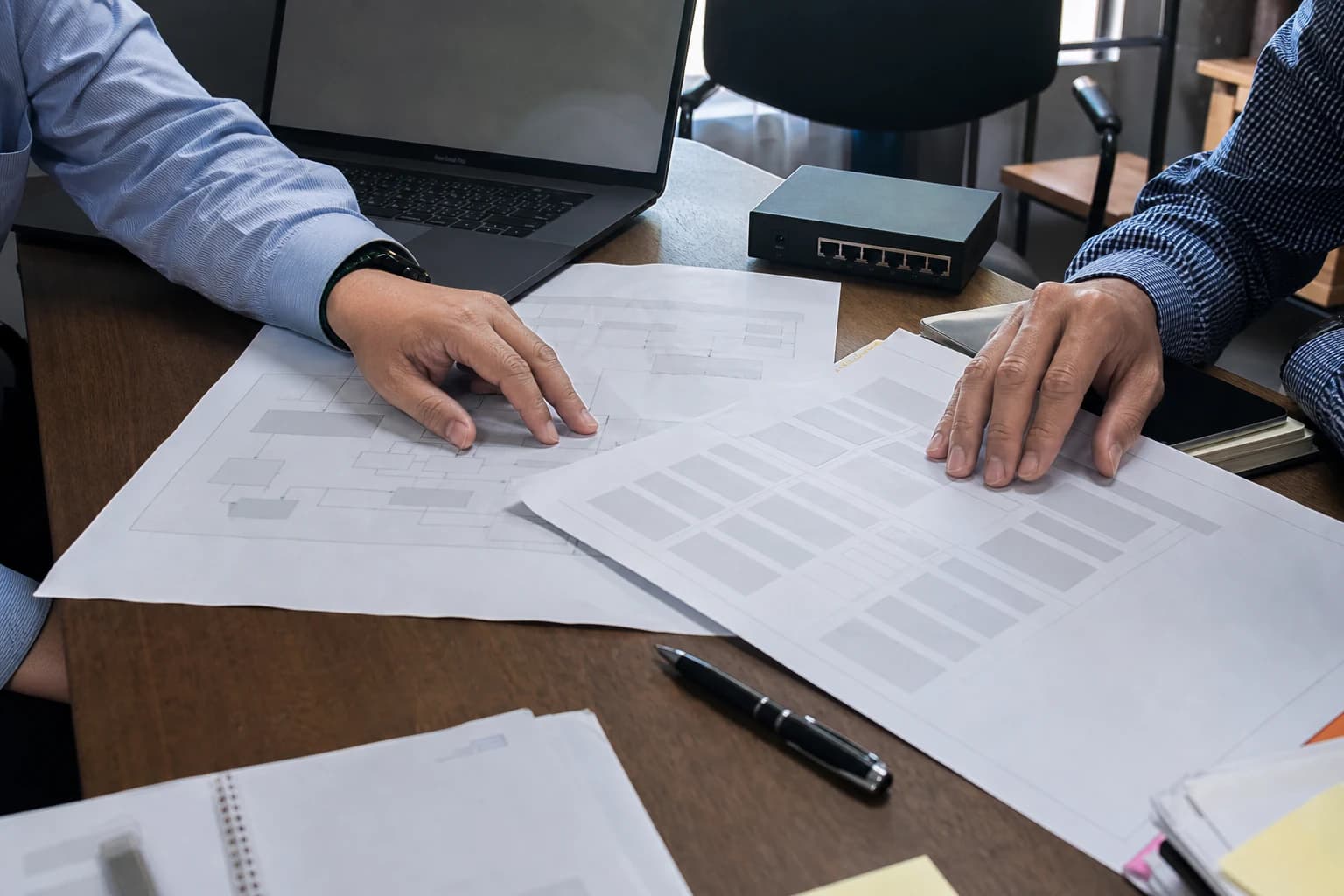 Hai người đang sắp xếp sơ đồ kiến trúc, checklist và thiết bị thành một bộ bằng chứng có thể rà soát